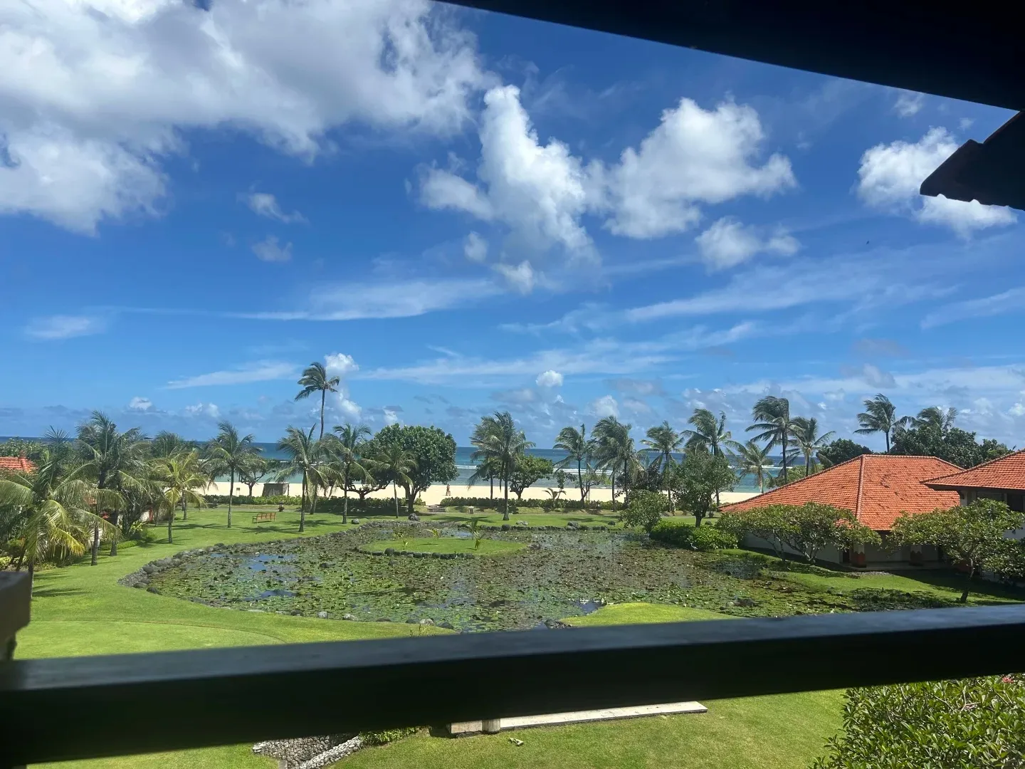 The view from a Grand Hyatt balcony over a lily pond and lawns to the beach and sea