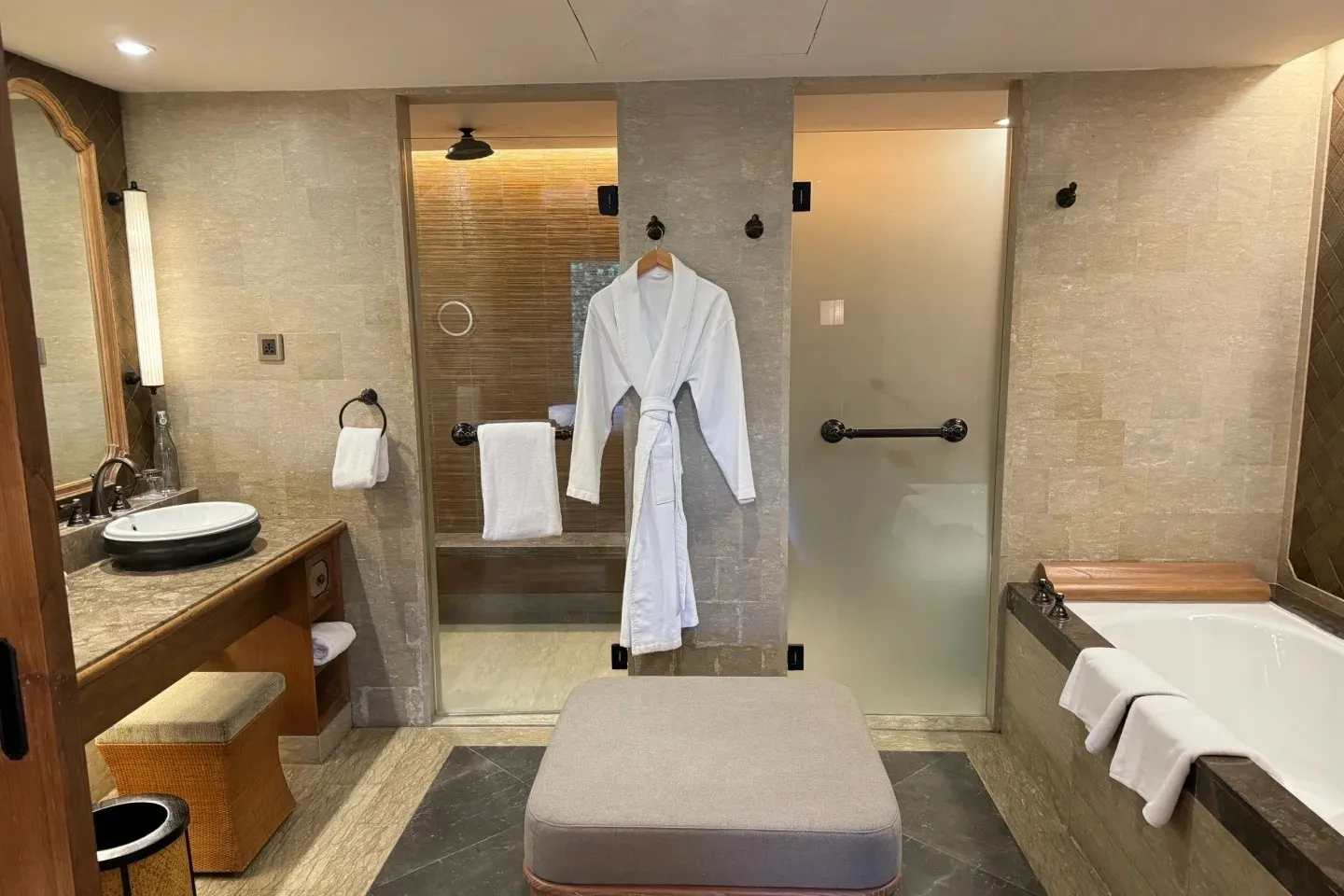 A Hyatt Regency bathroom with a stone vanity, a glass rain shower and a built-in bathtub