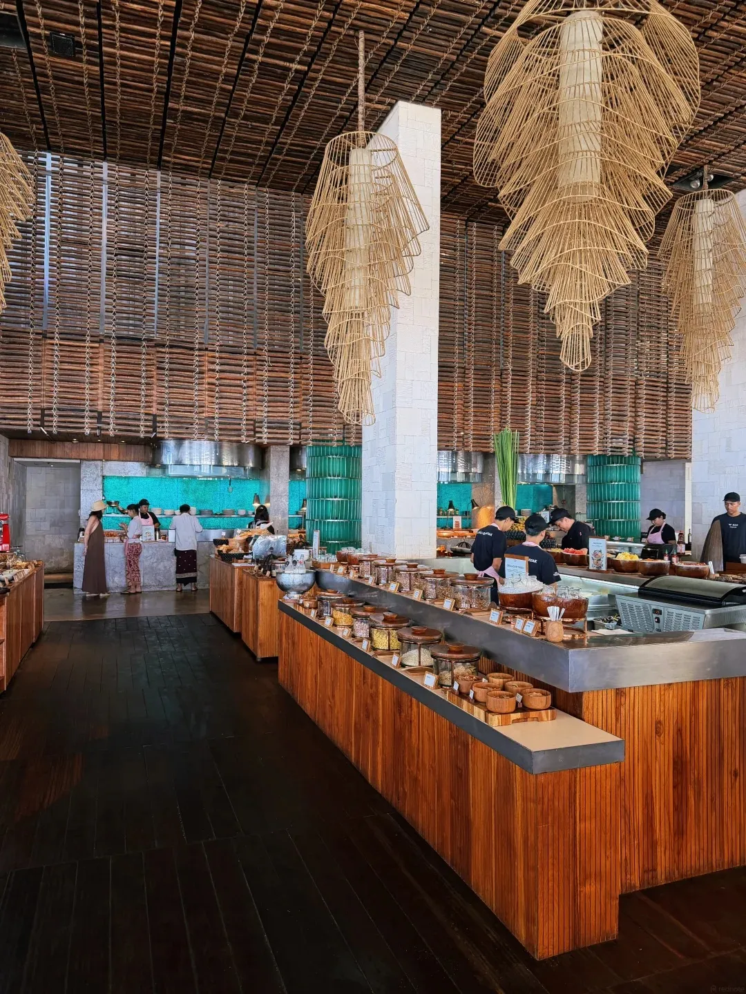 The long timber breakfast buffet under hanging rattan lamps, with chefs at the stations behind