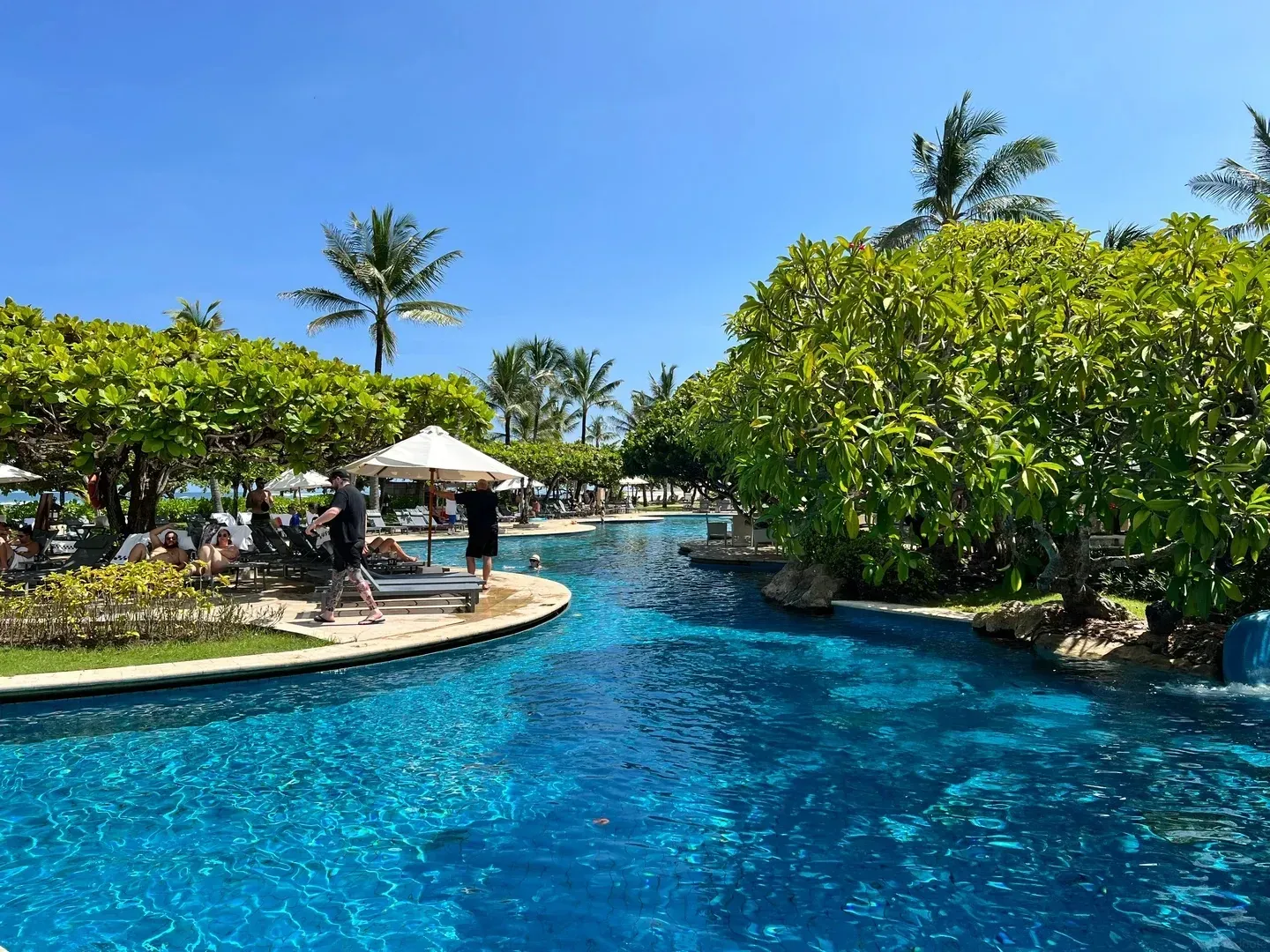 The winding river pool running between islands of frangipani trees towards the beach