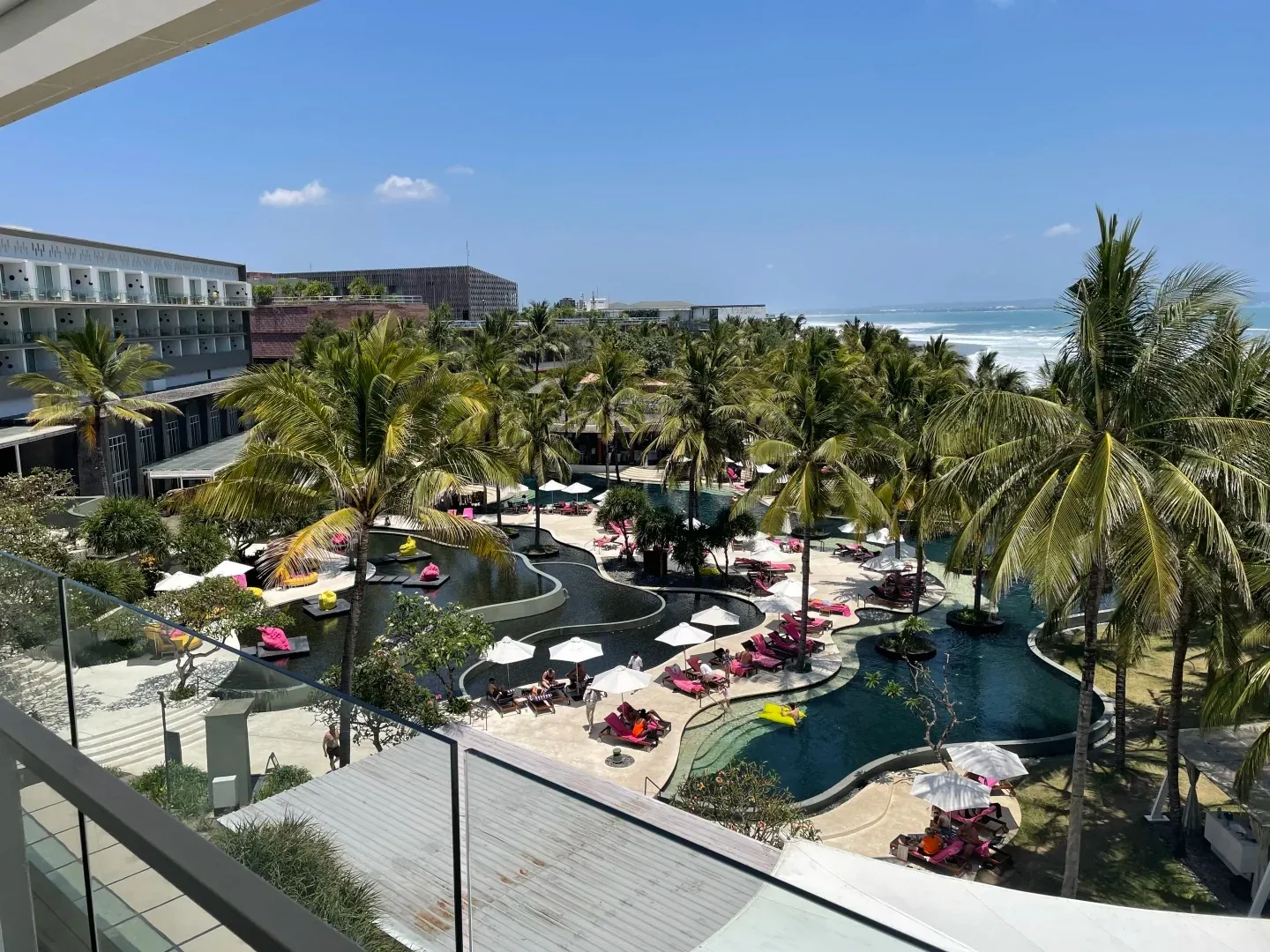 Looking down on the winding pool and its pink and red loungers, with the sea behind