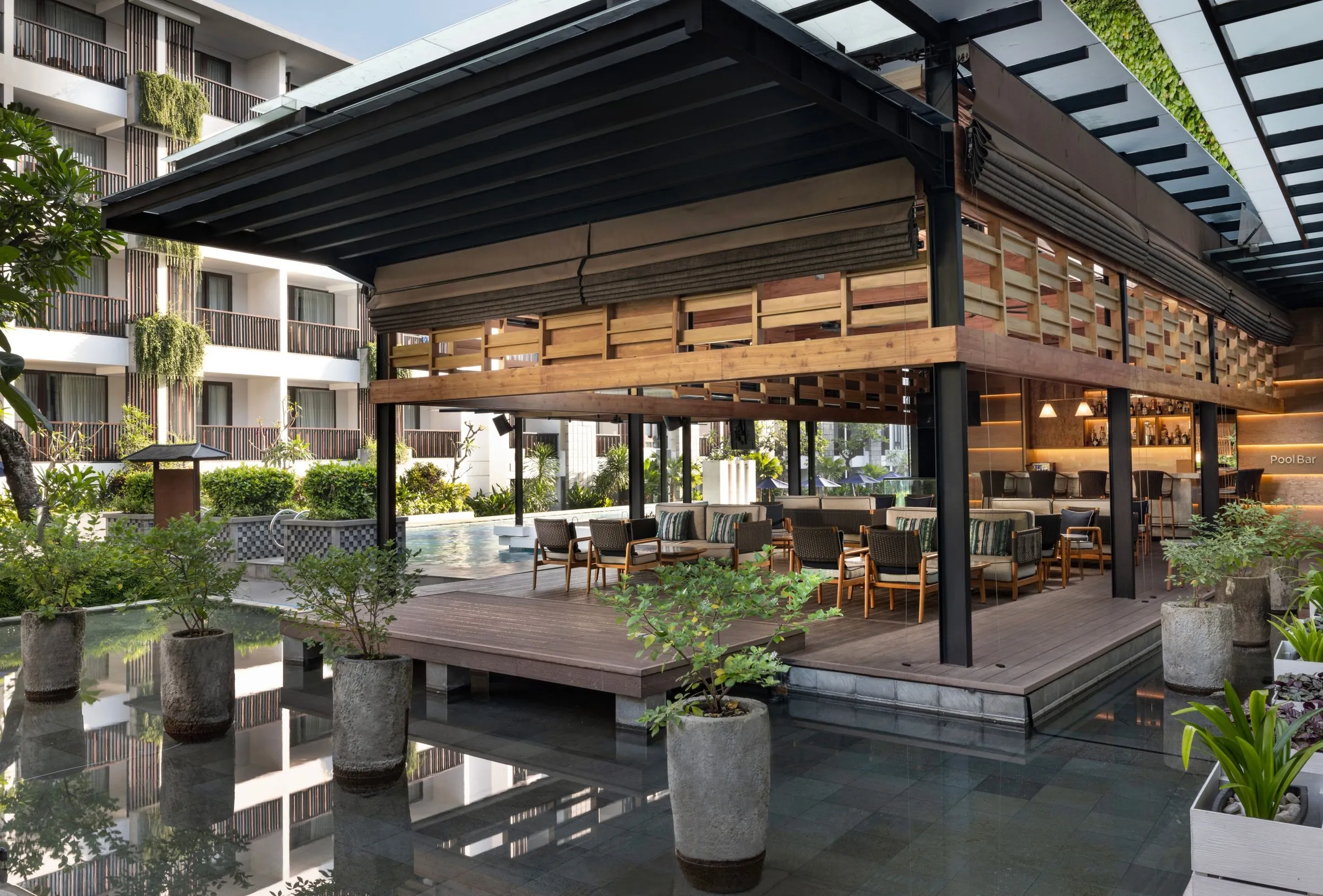 The pool bar pavilion on a deck over a reflecting pond, with lounge seating looking onto the pool