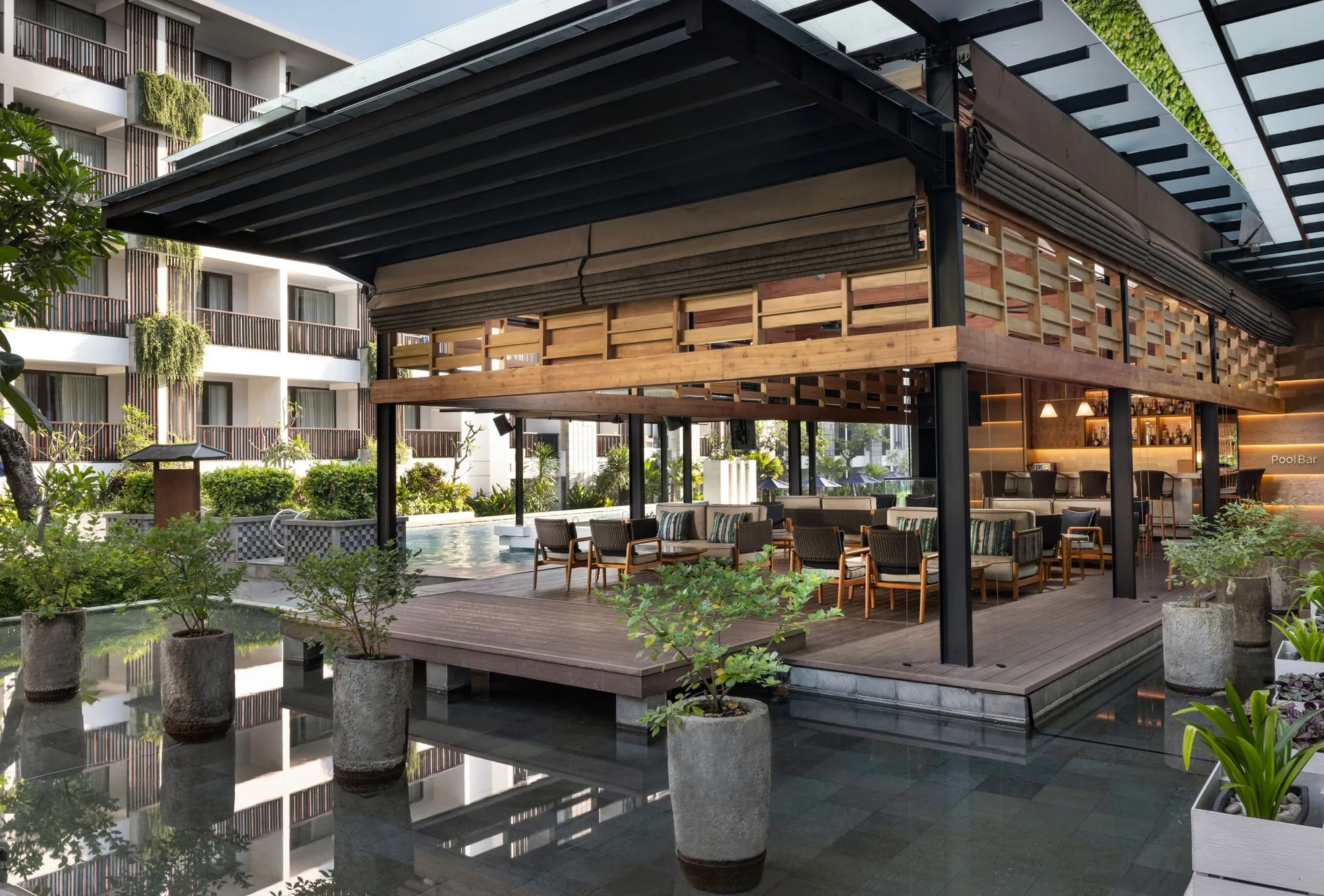 The pool bar pavilion on a deck over a reflecting pond, with lounge seating looking onto the pool