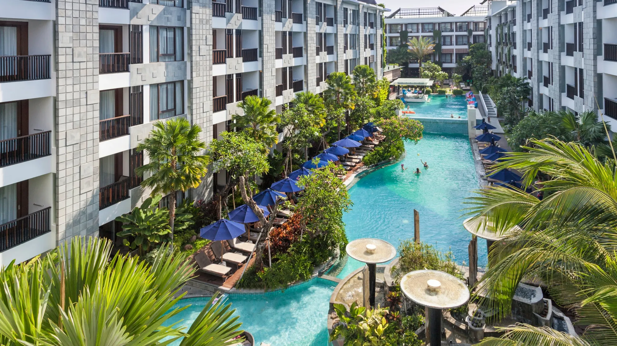 Looking down on the long lagoon pool winding between the room wings, lined with blue umbrellas and palms