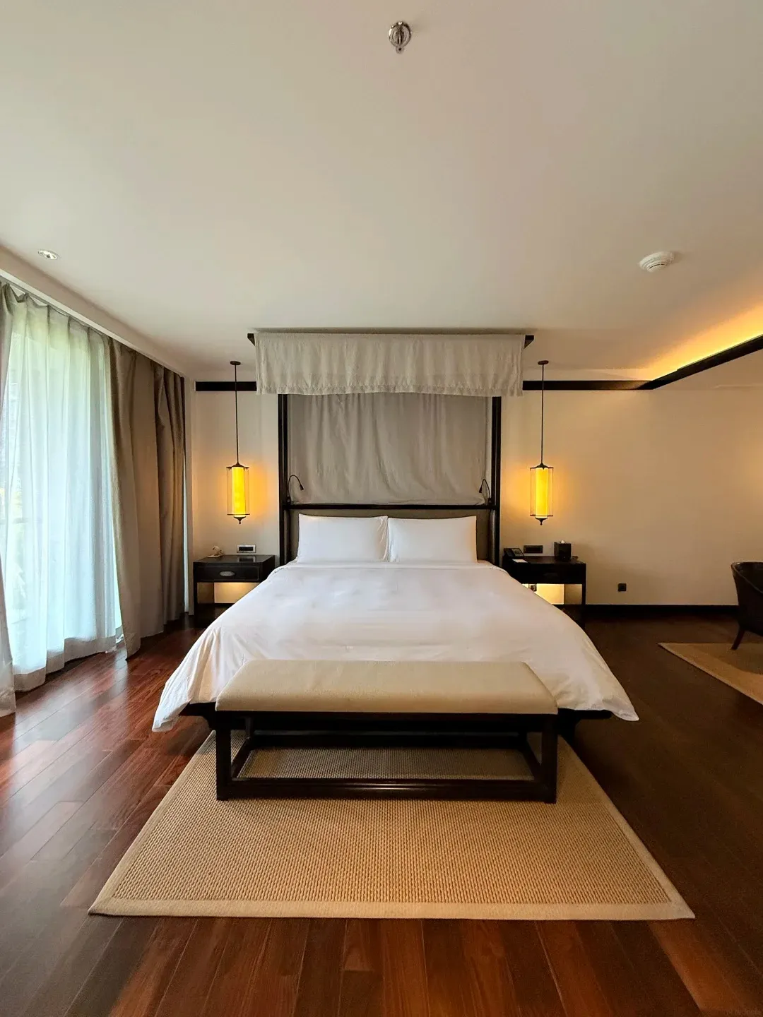 A Kempinski bedroom with a canopy bed on dark timber floors